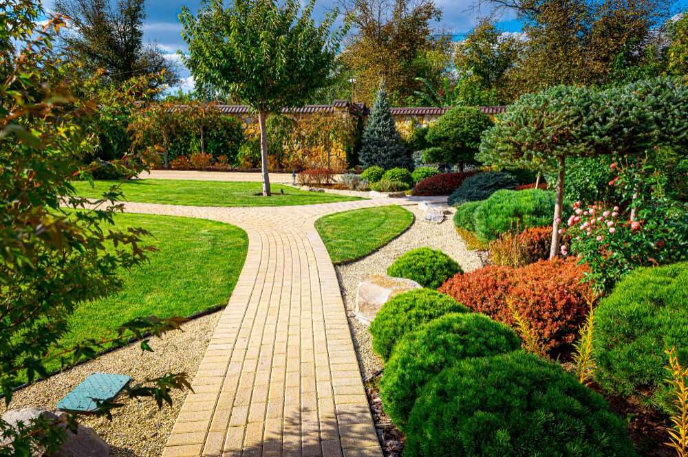 Sustainable landscaping in Etowah featuring a winding brick pathway surrounded by native plants, shrubs, and trees, promoting ecological balance and water conservation.