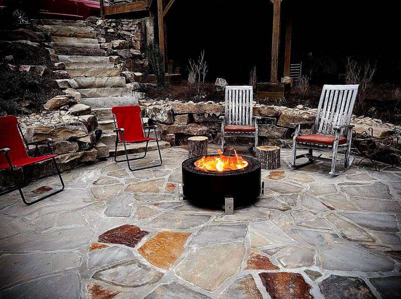 Craft Your Dream Outdoor Kitchen Outdoor firepit surrounded by red and white chairs on a stone patio, enhancing outdoor kitchen ambiance and social gatherings.