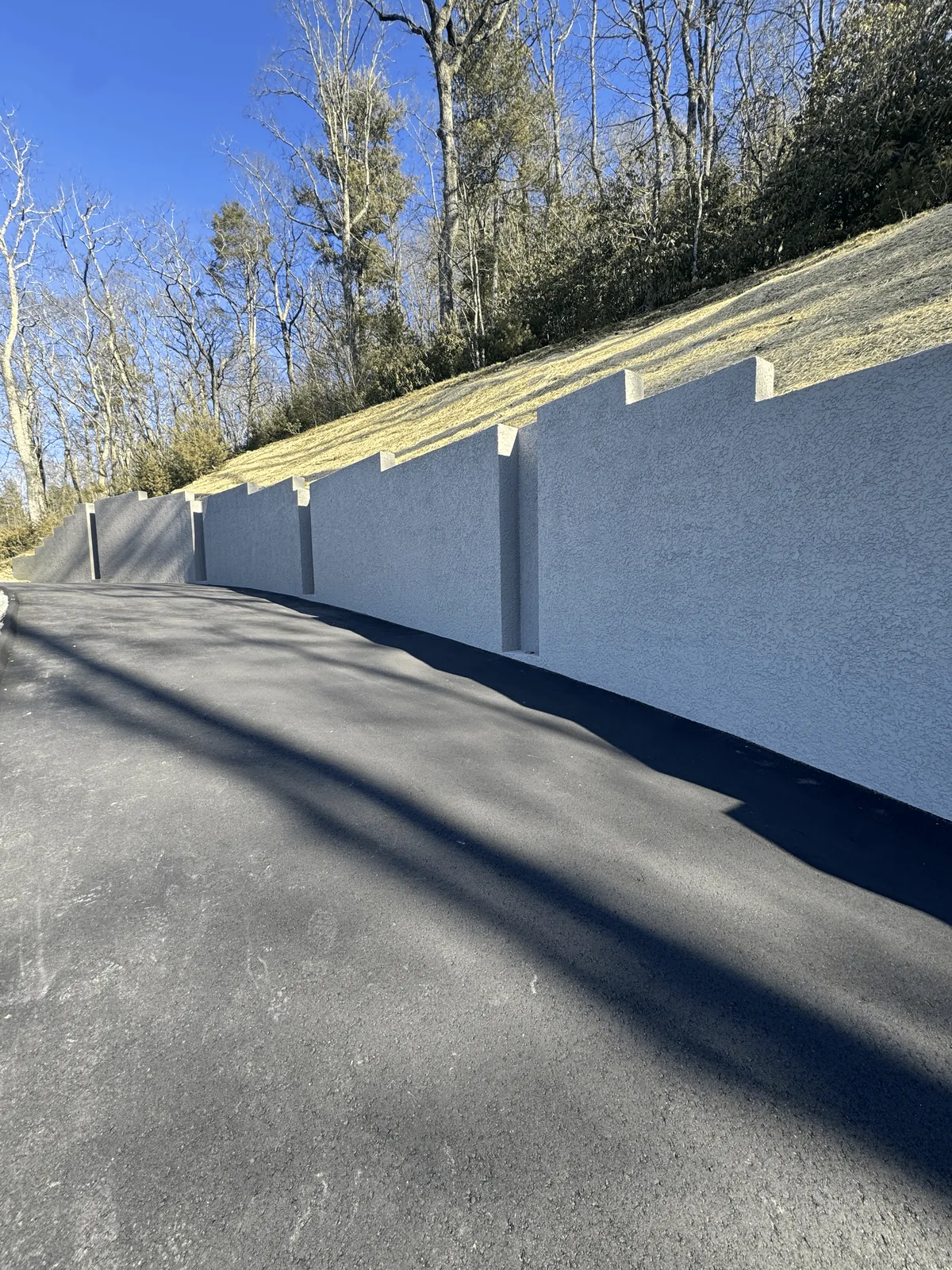 Finished masonry retaining wall built beside a steep residential driveway