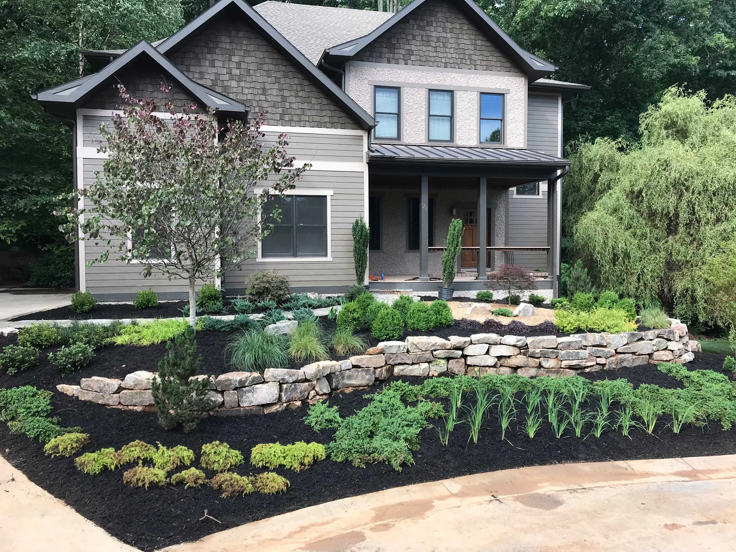 Tiered natural-stone retaining walls shaping a landscaped residential front yard